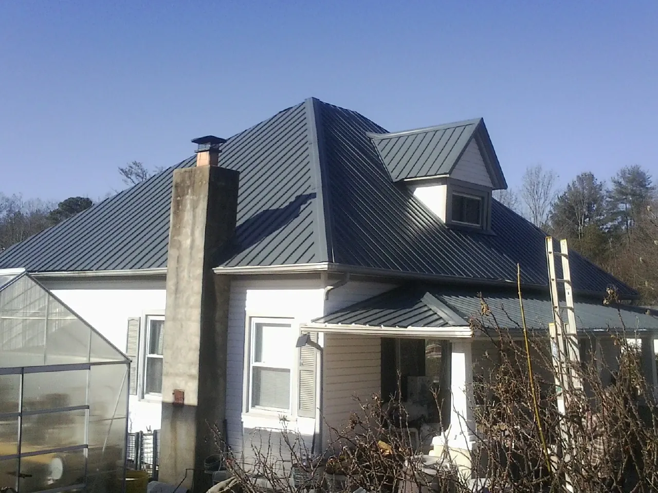 Dark blue standing seam metal roof on a white farmhouse with dormer — Slate & Tile Roof Repair by Roofing Brothers in Kingston Springs