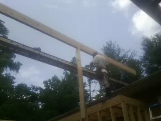 Carpenter setting a ridge beam over a new addition frame — Ice Dam Removal by Roofing Brothers in Kingston Springs