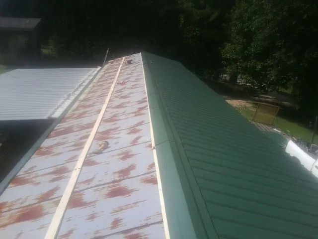 Old rusted panels beside newly installed green metal roofing — Wind Damage Roof Repair by Roofing Brothers in Kingston Springs