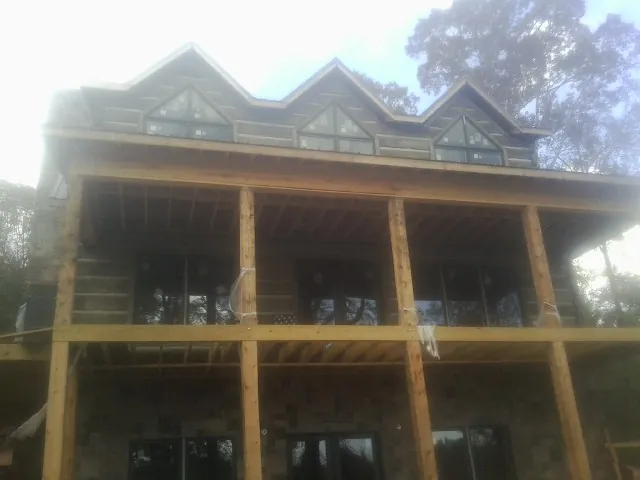 Dormers and porch framing on a large log home under construction — Roof Coating work by our crew in Kingston Springs