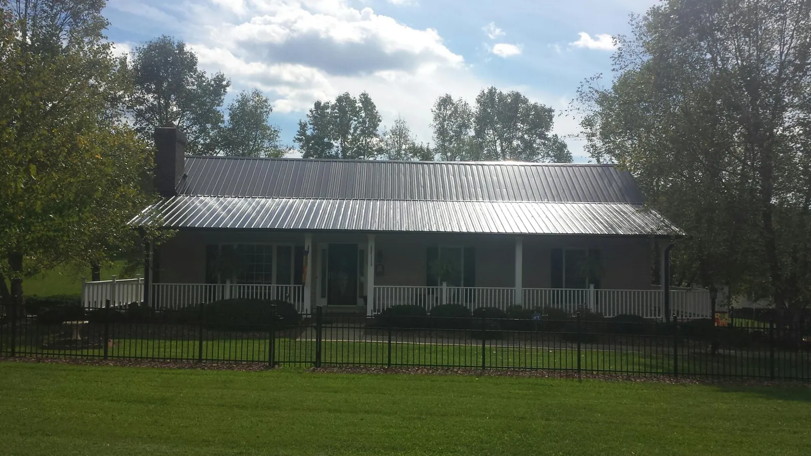 Gray metal roof on a brick ranch with a full width front porch — Gutter Guard Installation work by our crew in Kingston Springs