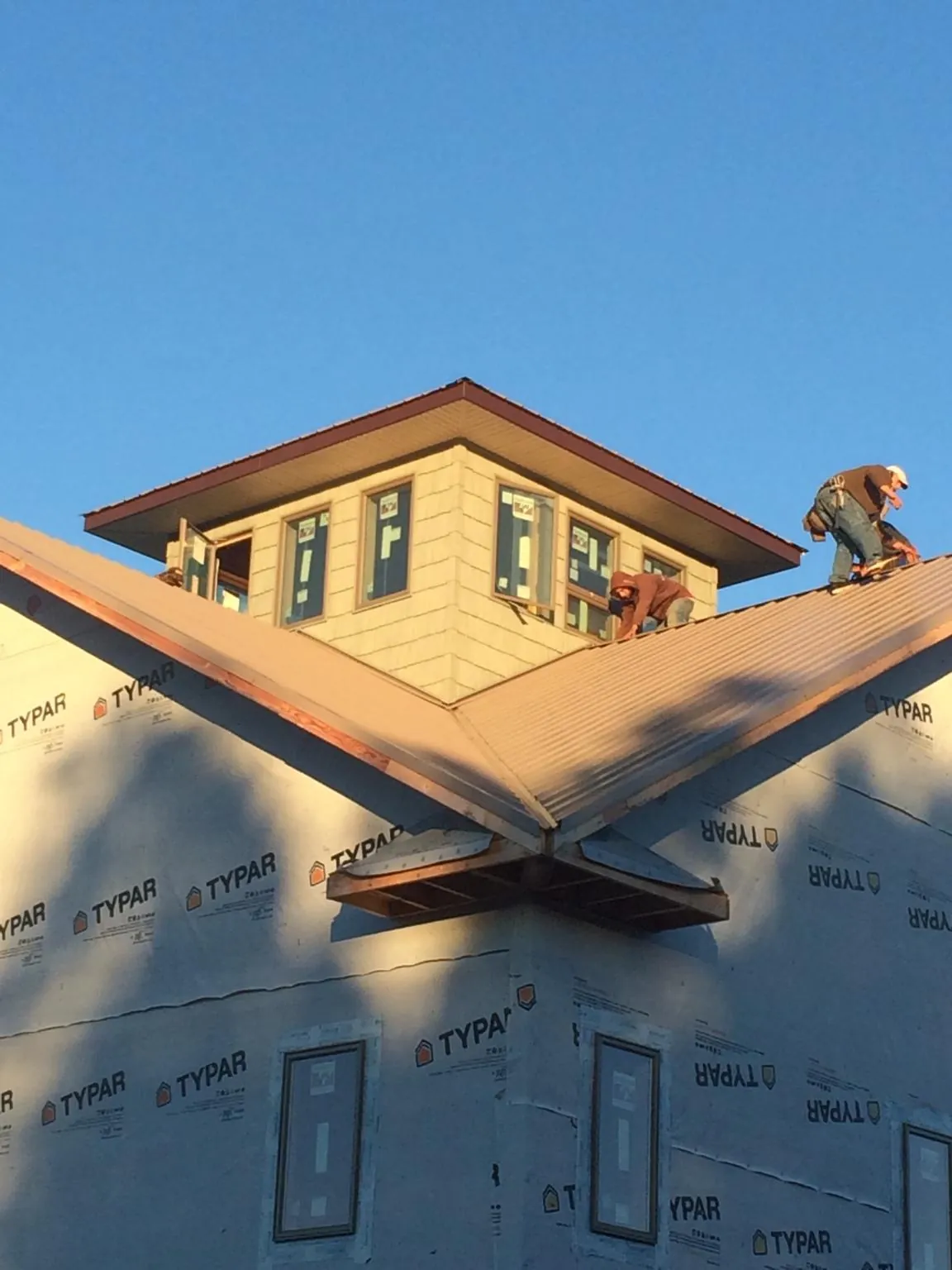 Roofers working around a rooftop cupola on a new metal roof at sunset — Roof Waterproofing in Kingston Springs by Roofing Brothers
